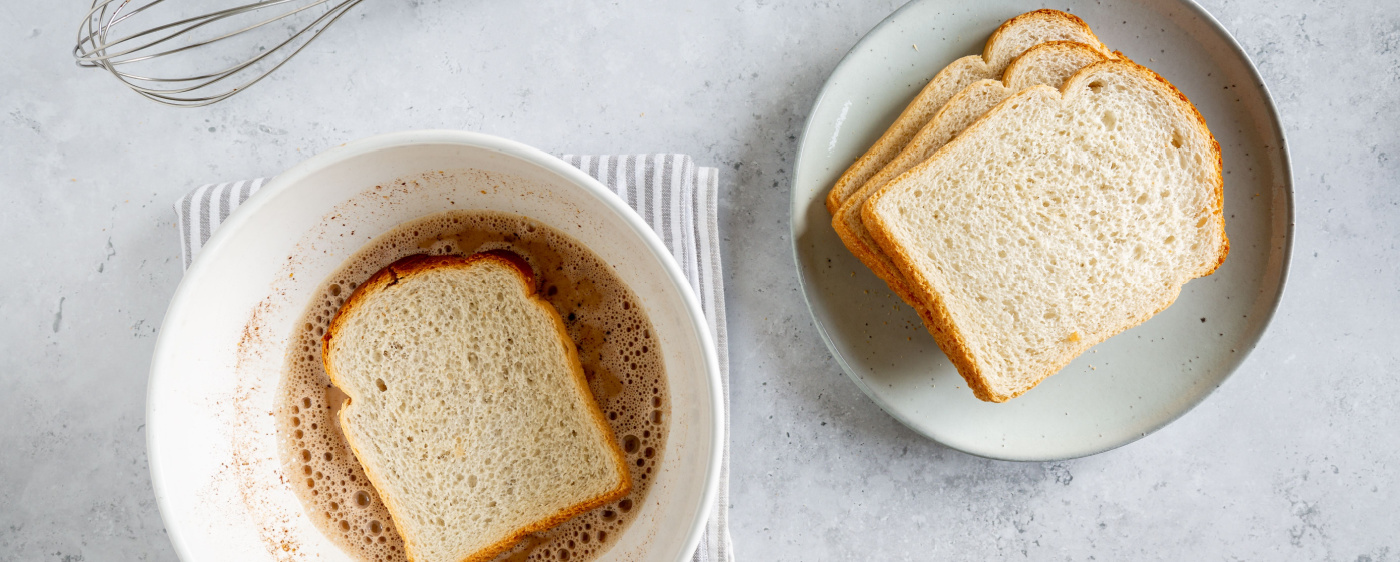 Bread sitting in a french toast egg mixture.