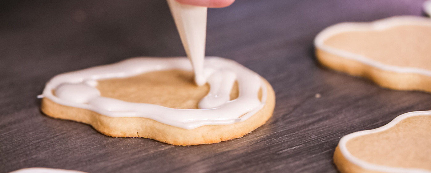 Icing being piped onto a sugar cookie.