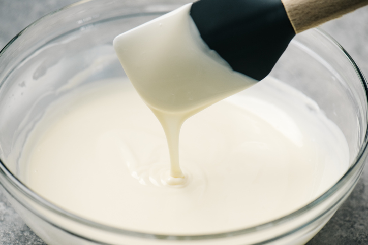 White chocolate frosting being mixed in a bowl.