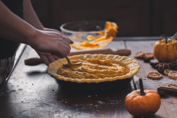 woman preparing pumpkin pie for the holidays at home - making pumpkin pie stock pictures, royalty-free photos & images