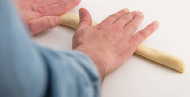 rolling trofie dough into long strings. - roll pretzel dough stock pictures, royalty-free photos & images