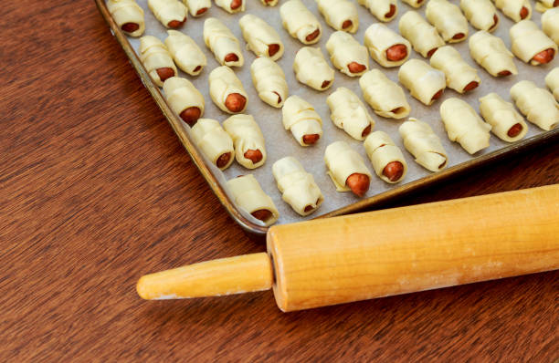 close up of plate with fresh homemade pigs in blanket on a table - making pigs in a blanket stock pictures, royalty-free photos & images