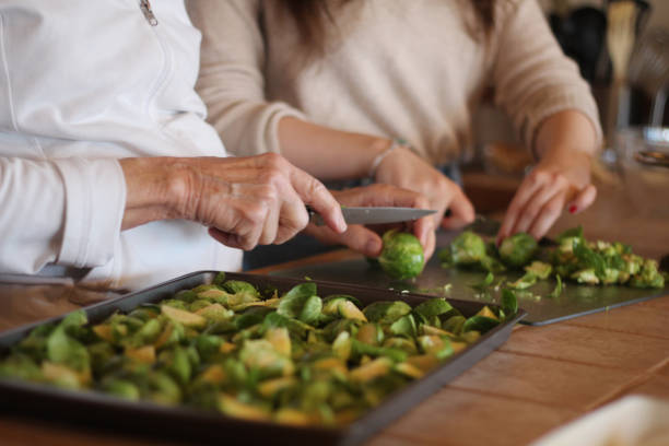 close up of hands chopping brussels sprouts for thanksgiving. - brussels sprouts stock pictures, royalty-free photos & images