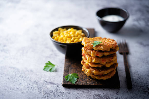 corn fritters in a plate with sour cream sauce - corn fritters stock pictures, royalty-free photos & images