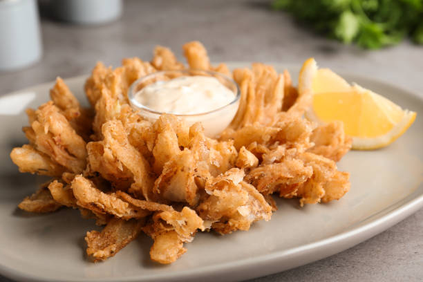 fried blooming onion with dipping sauce served on table, closeup - blooming onion fried stock pictures, royalty-free photos & images