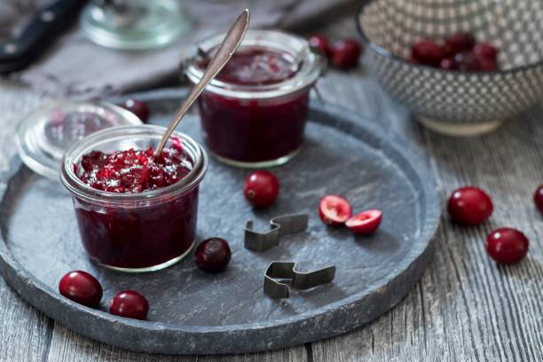 preserving glasses of cranberry jam and fresh cranberries - cranberry sauce stock pictures, royalty-free photos & images