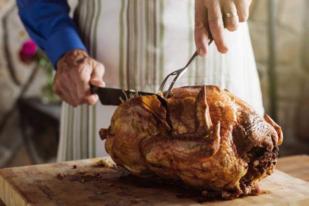 man carving fresh roasted turkey at home - thanskgiving turkey stock pictures, royalty-free photos & images