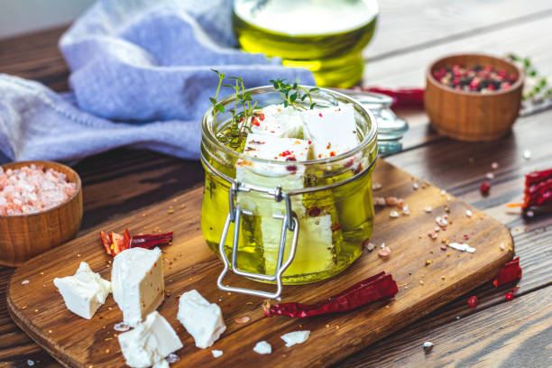 feta cheese marinated in olive oil in glass jar - marinated feta stock pictures, royalty-free photos & images