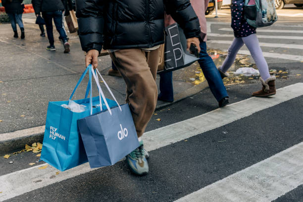 Shopper carries Alo Yoga and HOKA bags near Macy's flagship store in New York, US, on Sunday, Dec. 8, 2024. US consumer borrowing increased in...