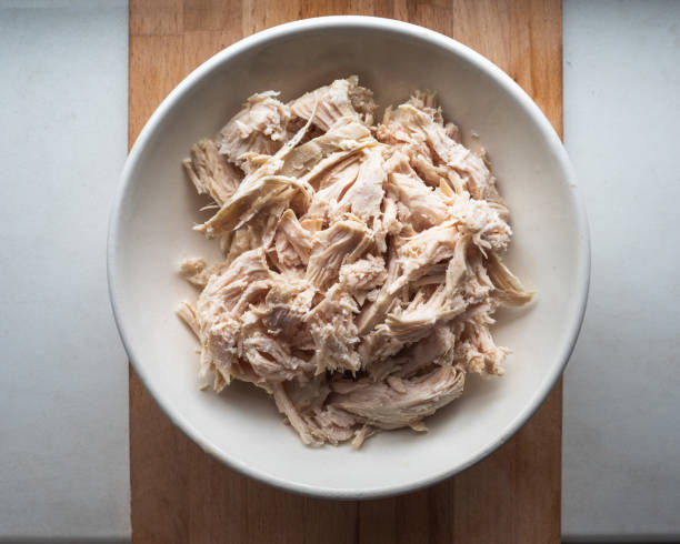 chopped chicken meat for salads in a deep plate is on the kitchen board - shredded chicken stock pictures, royalty-free photos & images