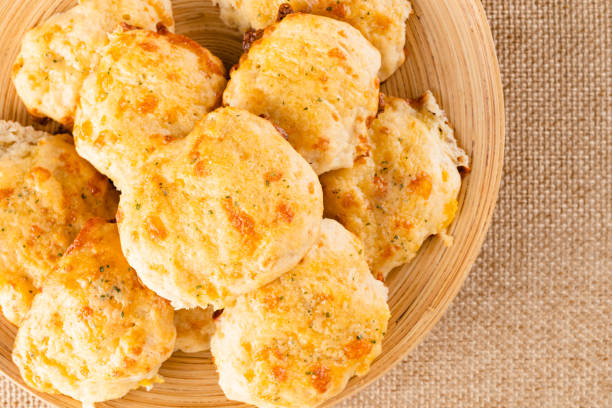 fresh baked cheese biscuits close-up on a wooden plate, flat lay - cheddar biscuit dough stock pictures, royalty-free photos & images