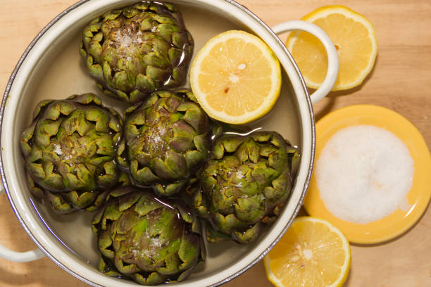 artichokes cooked with lemon and salt in the pot with water - artichoke in lemon water stock pictures, royalty-free photos & images