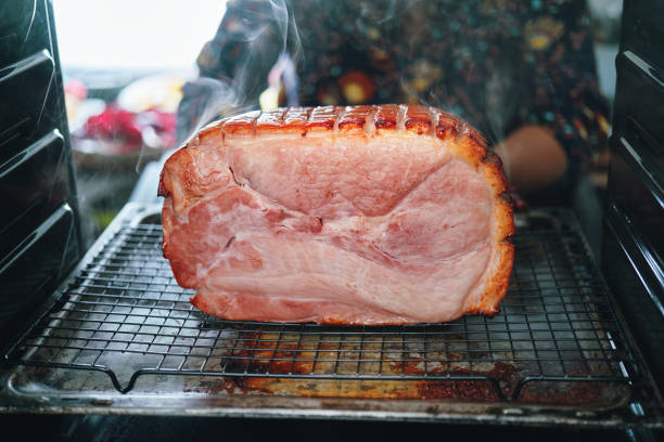 baking christmas ham in the oven - honey baked ham carving stock pictures, royalty-free photos & images