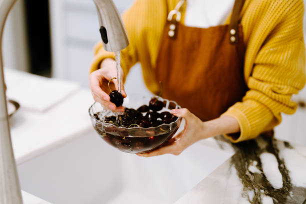 asian young woman washing fruits and vegetables at home. - making olive tapenade stock pictures, royalty-free photos & images