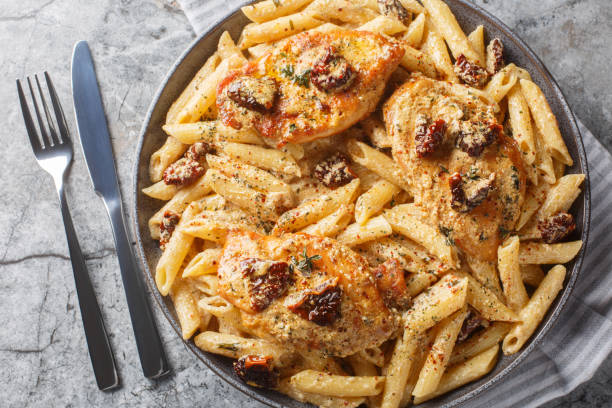 marry me chicken penne with creamy pasta, tender chicken breast, parmesan cheese, sun-dried tomatoes, and herbs closeup on the plate. horizontal top view - marry me chicken stock pictures, royalty-free photos & images