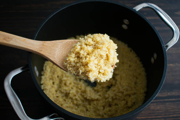 a spoonful of cooked quinoa - making quinoa stock pictures, royalty-free photos & images