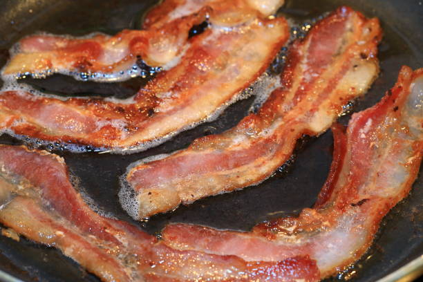 sizzling bacon in the frying pan - cooking bacon stock pictures, royalty-free photos & images