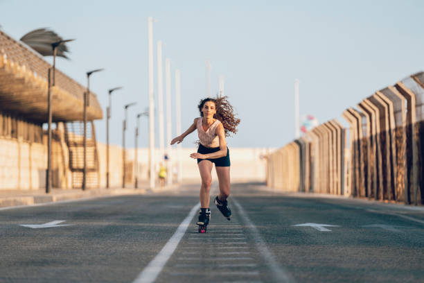 young woman inline skating on boardwalk at the coast - roller blading stock pictures, royalty-free photos & images