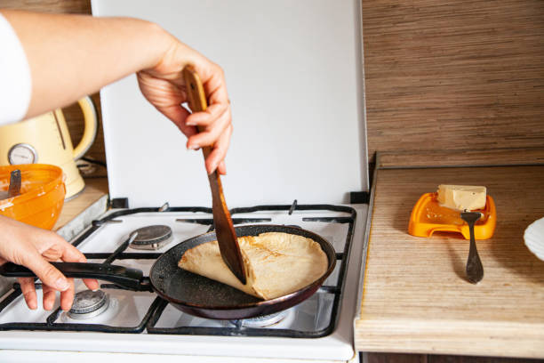 woman frying blini in home kitchen - crepes recipe stock pictures, royalty-free photos & images