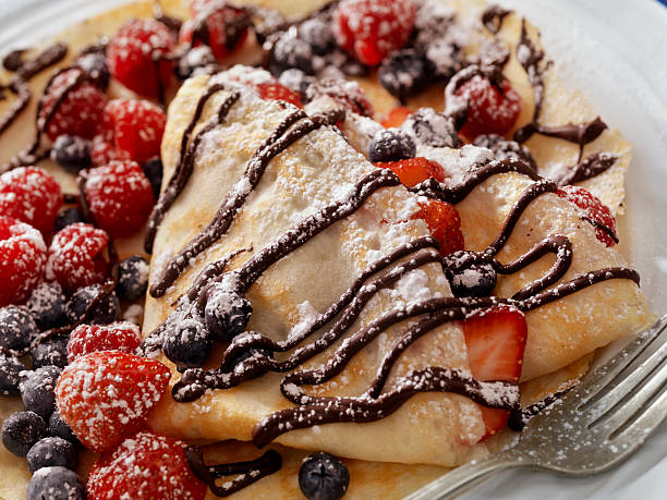 crepes with fresh berries, chocolate sauce and powdered sugar - crepes with berries stock pictures, royalty-free photos & images